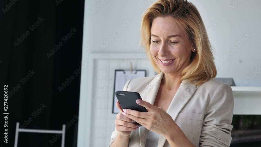 Portrait adult elegant woman using smartphone indoors.Smiling businesswoman wearing suit holding smart phone. Lady chatting in social media or use web application or shopping online. Happy cheerful Portrait adult elegant woman using smartphone indoors.Smiling businesswoman wearing suit holding smart phone. Lady chatting in social media or use web application or shopping online. Happy cheerful