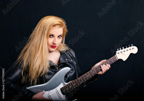 Beautiful blonde girl in rock style on a black background.
