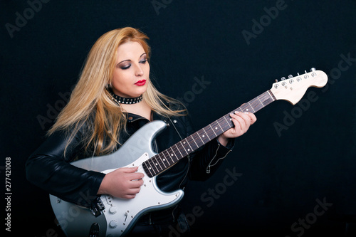 Beautiful blonde girl in rock style on a black background.