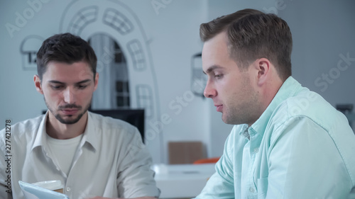 Small business startup team. Job interview concept. Interviewer caucasian friendly businessman asking questions. Nervous candidate mixed race male holding a cup of coffee in hand