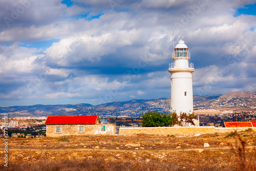 White lighthouse in Paphos Archaeological Park Cyprus and old house.