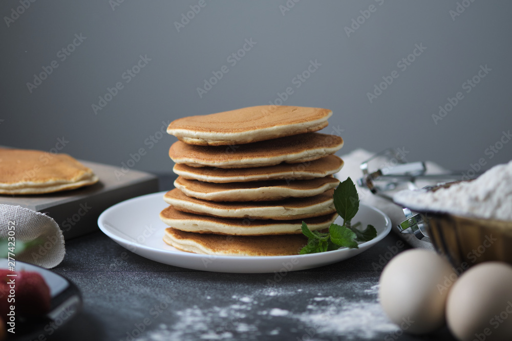 One-on-one pancakes cooked for breakfast. On the table are products from which the dish was prepared and berries. One-on-one pancakes cooked for breakfast. On the table are products from which the dish was prepared and berries.