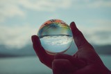 Snow capped mountains in Glacier Bay National Park and Preserve, reflected in crystal ball held by and and