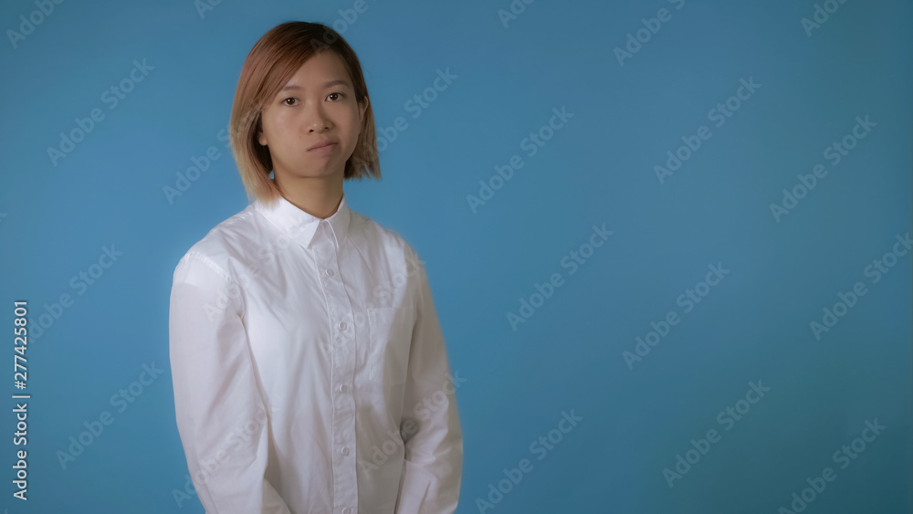 portrait young asian female posing showing hand gesture stopping crossing harms on blue background in studio. attractive korean woman with blond hair wearing white casual shirt looking at the camera portrait young asian female posing showing hand gesture stopping crossing harms on blue background in studio. attractive korean woman with blond hair wearing white casual shirt looking at the camera