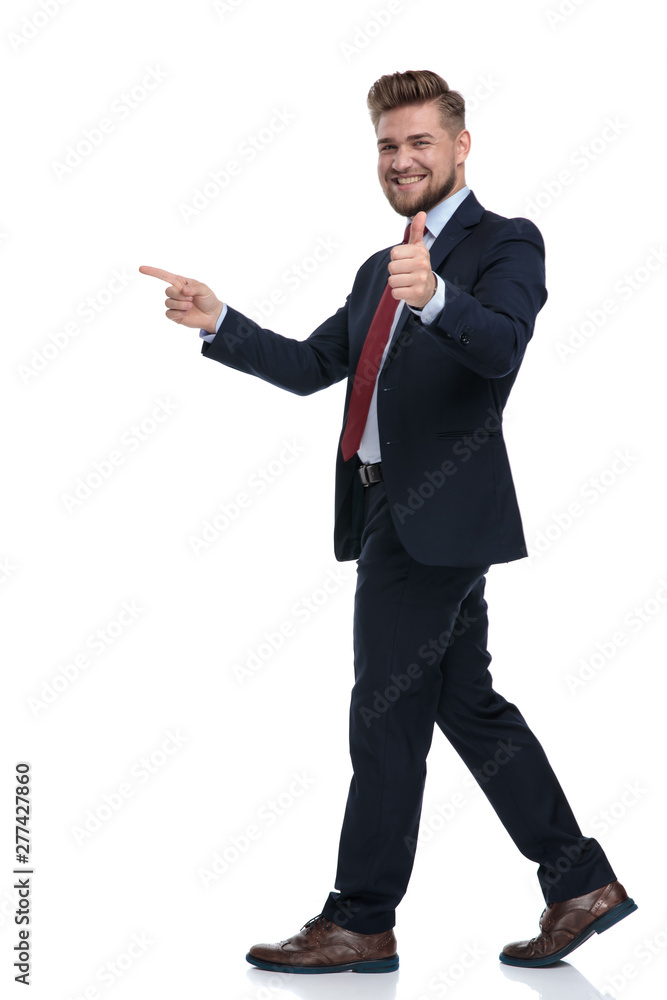 Happy businessman stepping and pointing while gesturing ok
