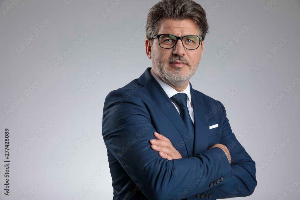 Confident businessman standing with his hands folded at his chest Confident businessman standing with his hands folded at his chest