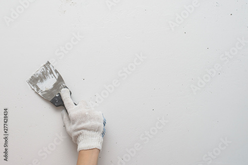 Working tool, spatula in hand against the background of a white wall, work plasterer. Putty walls with their own hands.