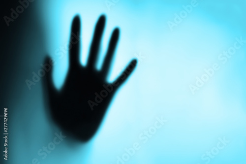 Blurry female hand reaching out and touching glass with Blue light