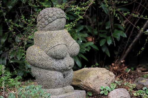 A statue replica of the ancient ”Venus from Willendorf” in a swedish garden in the spring blooming. photo