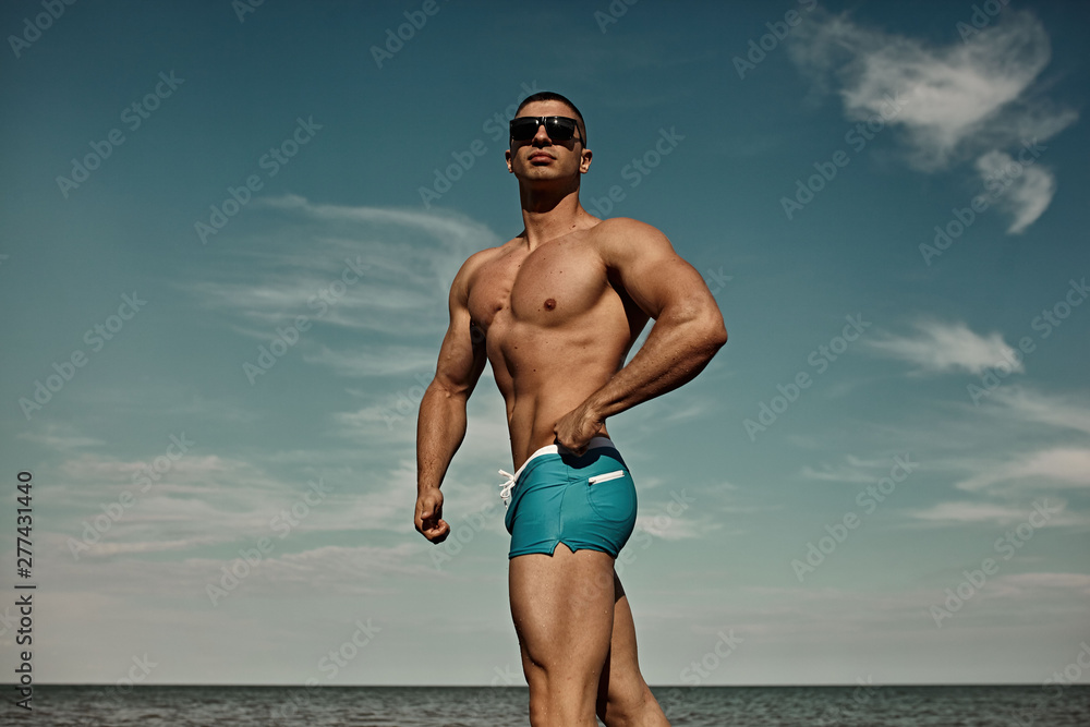 Summer vacation. Sexy muscular man on the beach in sunglasses..