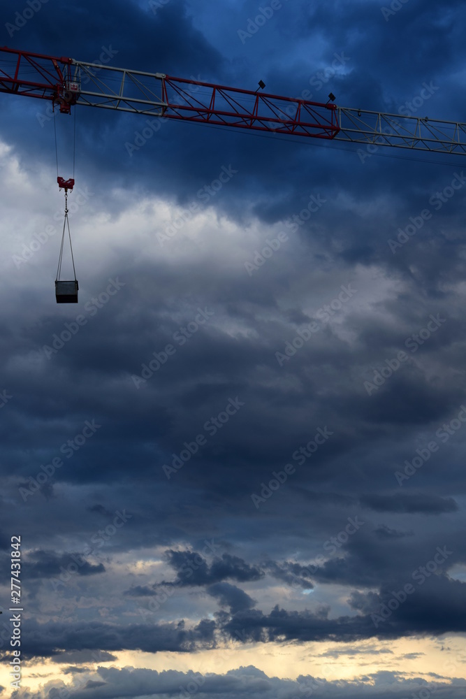 Dunkle düstere Gewitterwolken vor einer Baustelle mit einem Baukran Dunkle düstere Gewitterwolken vor einer Baustelle mit einem Baukran