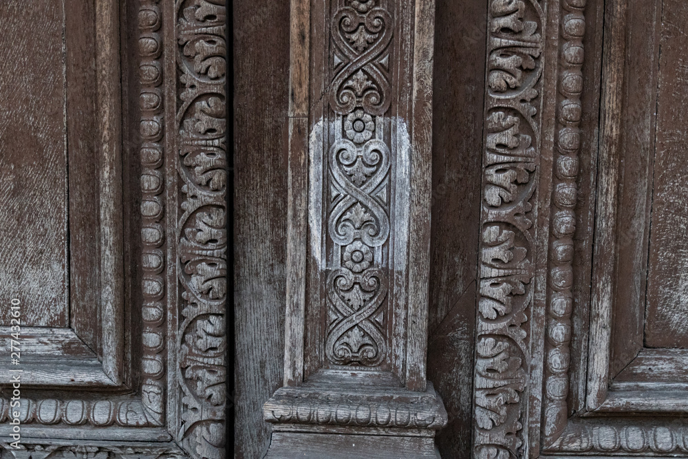 Ornamental carving wooden surface closeup of ancient door of Louvre museum in Paris France. Ornate wood texture of old double door closeup. Weathered wooden patterns of doorway panels.
