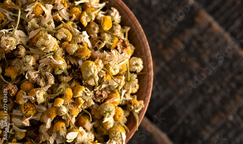 A Bowl of Dried Chamomile Flowers on a Wooden Table