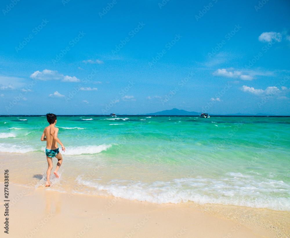 Young boy running on beach looking at the blue ocean. Young boy running on beach looking at the blue ocean.