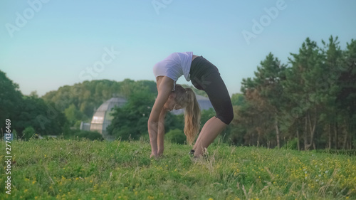 Workout outdoors. Woman at pilates in the park. Happy young athlete stretching body. every day sport routine for flexible. Caucasian gymnast trains in the park.