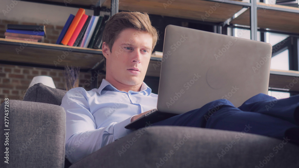 Man working with computer in studio apartment. Young businessman using wifi typing on laptop at home. Man working with computer in studio apartment. Young businessman using wifi typing on laptop at home.