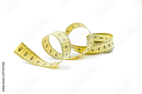 The yellow measuring centimetric tape curtailed by a spiral on a white background. Sewing accessories photo