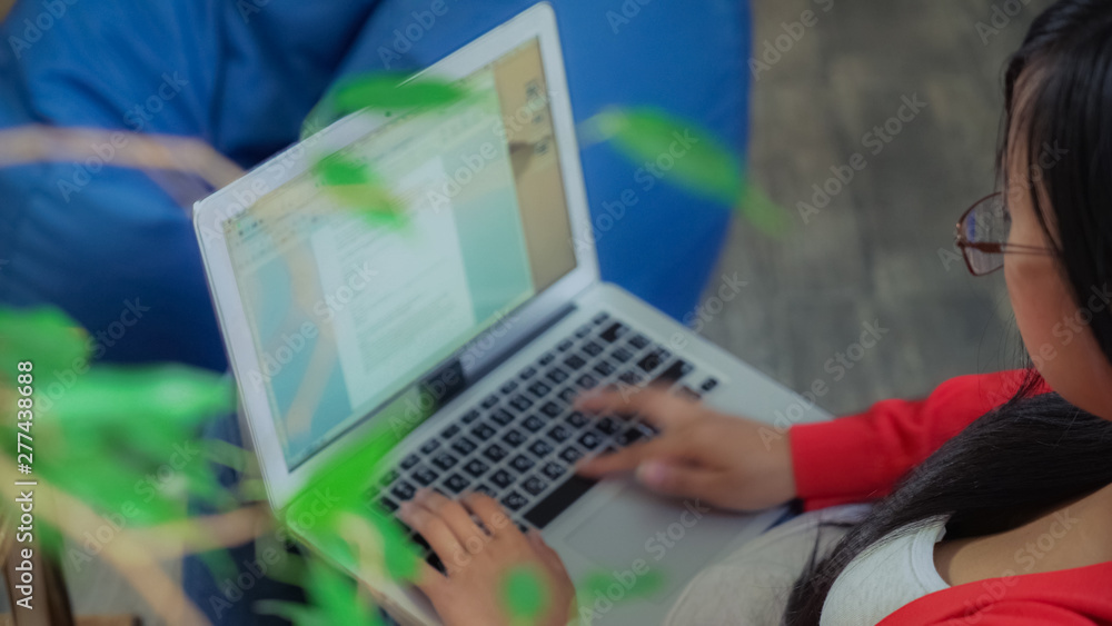 Back view woman working on the computer typing data. Girl holding laptop typing text. Businesswoman in eyeglasses and black long hair works using internet. Back view woman working on the computer typing data. Girl holding laptop typing text. Businesswoman in eyeglasses and black long hair works using internet.
