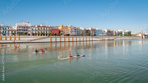Seville, Spain. View of the Guadalquivir river. Generic canoeists train on the river. Seville is a training site for canoeists from all countries. In the background typical Spanish houses