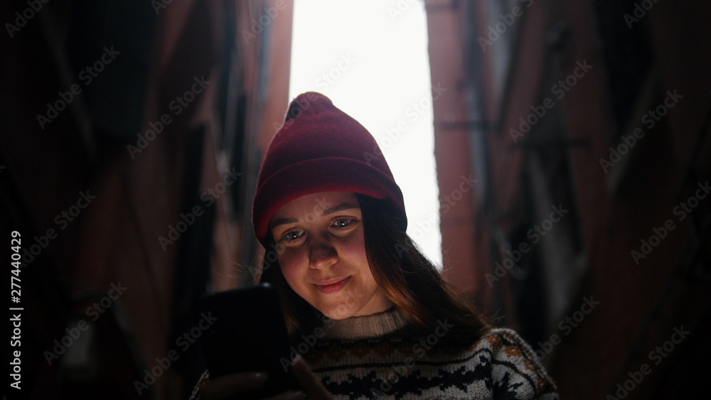 Woman on the narrow alley. Phone highlights her face Woman on the narrow alley. Phone highlights her face