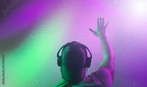 Obraz na plátně DJ raised his hand during a performance. Back view
