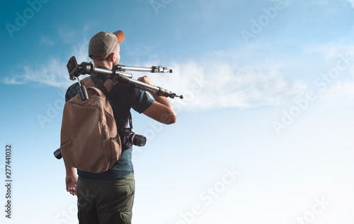 Photographer with photographic equipment looks into the distance.