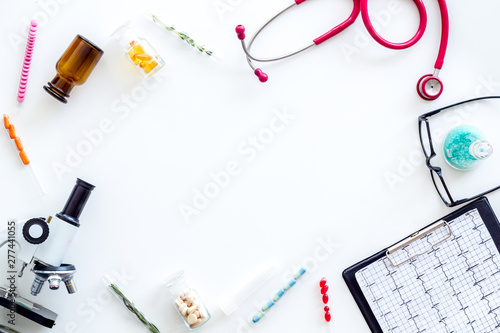 Medical tests on work table of doctor with microscope, cardiogram, test tube on white background top view copyspace