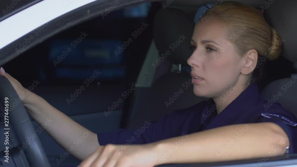 Tired upset female cop sitting in patrol car, pondering difficult investigation Tired upset female cop sitting in patrol car, pondering difficult investigation