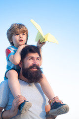 Kids playing with simple paper planes on sunny day. Father giving son ride on back in park. Father and son playing - family time together. Happy fathers day.