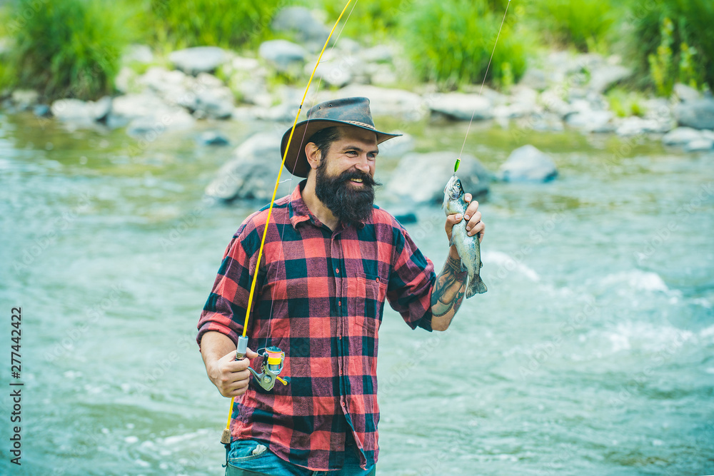 Obraz premium Bass fishing. Fisherman and trophy trout. River grayling on the hook. sport fishing. Method for catching trout. Fishing. Lure fishing. Trout.
