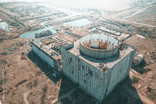 Aerial view of abandoned and ruined Nuclear Power Plant or station, round tower of atomic reactor, large industrial demolished building photo