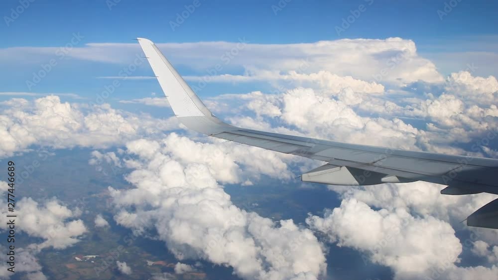 Large commercial airplane wing curving. The blue skyline view above the clouds from air plane window. Large commercial airplane wing curving. The blue skyline view above the clouds from air plane window.