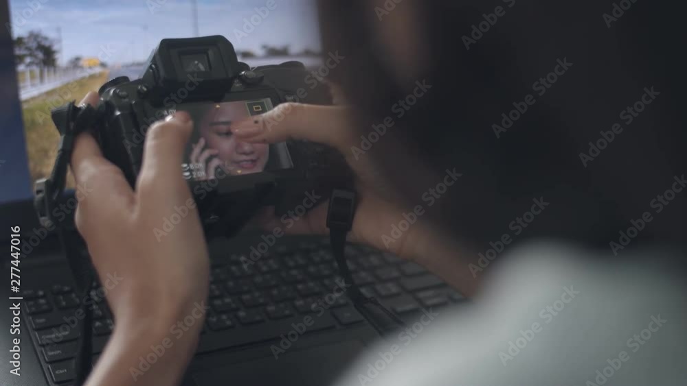 Close up hands young asian woman sitting on table checking her photo after take photo at home. Freelance photographer using computer editing photo. Close up hands young asian woman sitting on table checking her photo after take photo at home. Freelance photographer using computer editing photo.