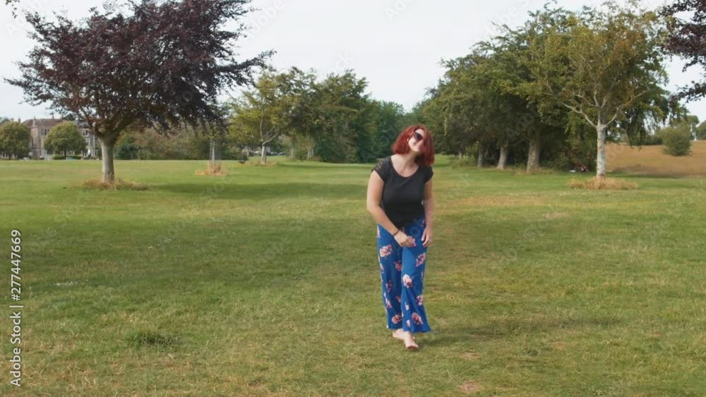 Pretty young woman with red hair throwing frisbee outdoors in green park Pretty young woman with red hair throwing frisbee outdoors in green park