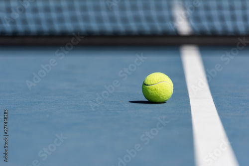 Tennis ball on blue tennis court.