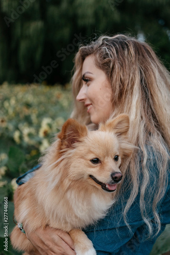 A young woman and her small dog in a sunflower field