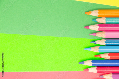 Colorful background with many pencils crayons pastels lined up on multi color backdrop - Top view flat lay photo