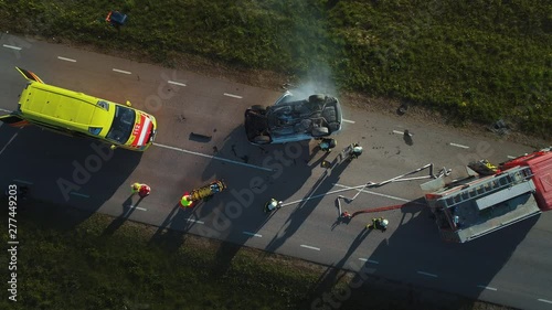 Aerial View: Rescue Team of Firefighters and Paramedics Work on a Car Crash Traffic Accident Scene. Preparing Equipment, First Aid Help. Saving Injured and Trapped People from the Vehicle. Zoom in photo