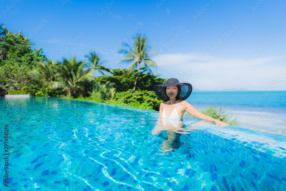 Portrait beautiful young asian woman relax in luxury outdoor swimming pool in hotel resort nearly beach sea ocean