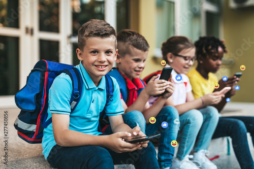 Group of happy elementary school students with smartphones. Primary education  friendship  childhood  and technology concept.