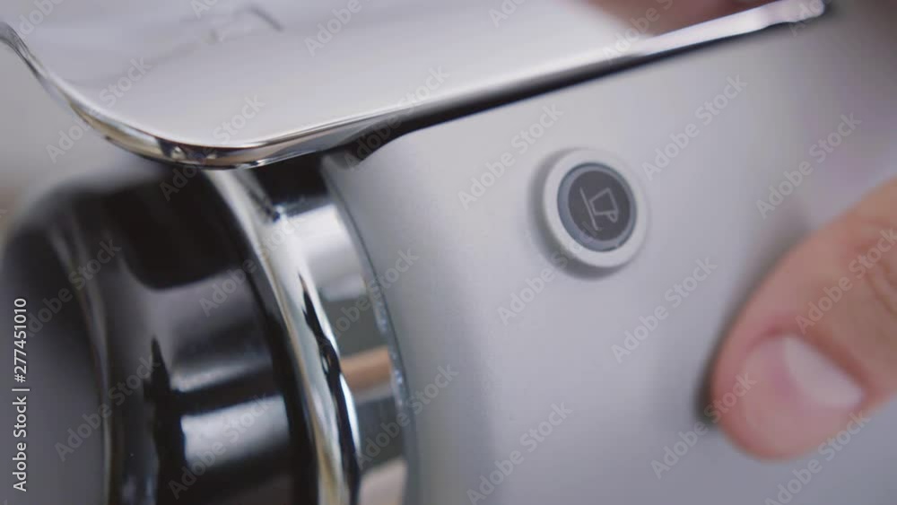 Closeup view of one's finger pressing round shaped button with symbol of cup on grey panel of modern automatic coffee machine, the button changes color to green. Closeup view of one's finger pressing round shaped button with symbol of cup on grey panel of modern automatic coffee machine, the button changes color to green.