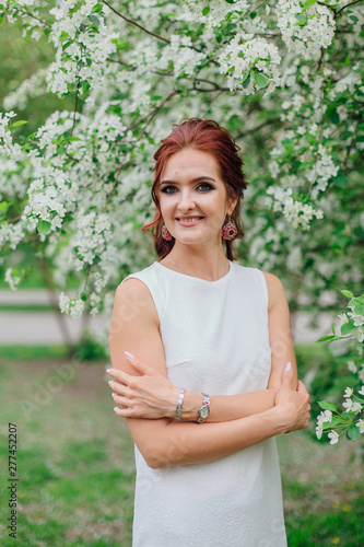 Charming woman wearing beautiful white dress under the apple tree