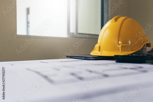 High angle view of housing plan blueprint with yellow safety helmet.