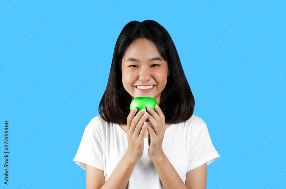 A young girl holding a green apple with the blue background A young girl holding a green apple with the blue background