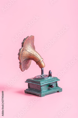 Antique gramophone on a pink background, copper and green