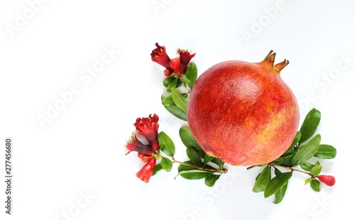 ripe pomegranate with pomegranate flowers and leaves on a light background