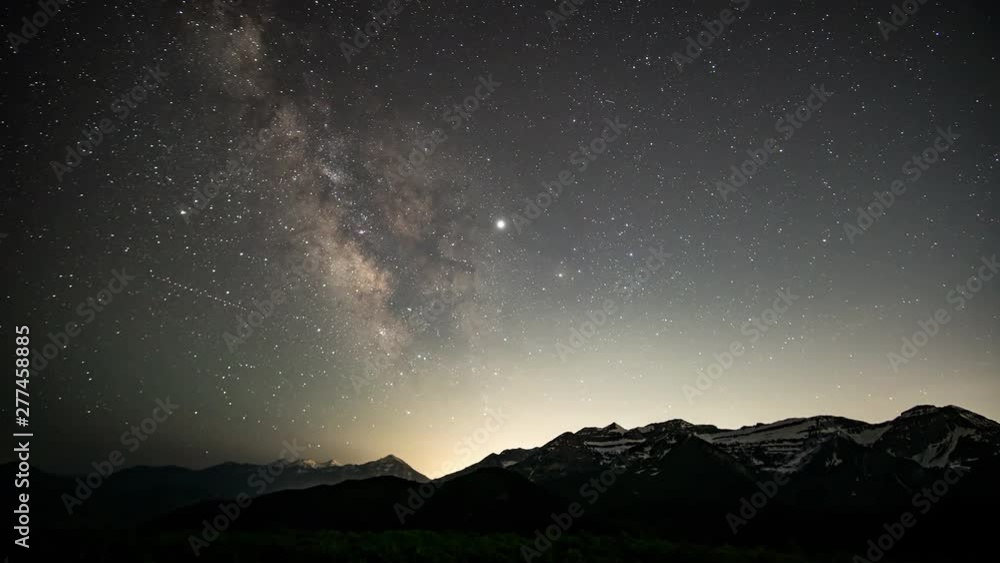 Star time lapse as city lights glow from behind mountain as the Milky Way moves through the sky in Utah. Star time lapse as city lights glow from behind mountain as the Milky Way moves through the sky in Utah.