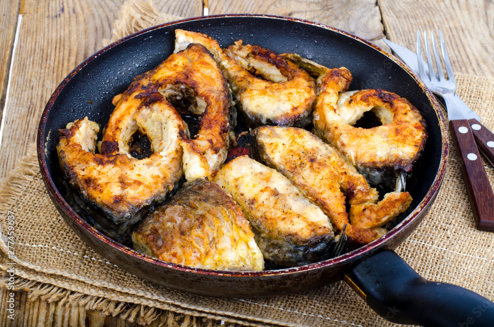 Old frying pan with fried fish on wooden table. Old frying pan with fried fish on wooden table.