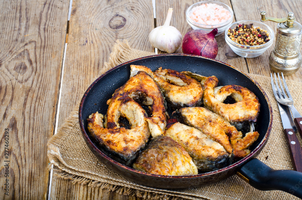 Old frying pan with fried fish on wooden table. Old frying pan with fried fish on wooden table.