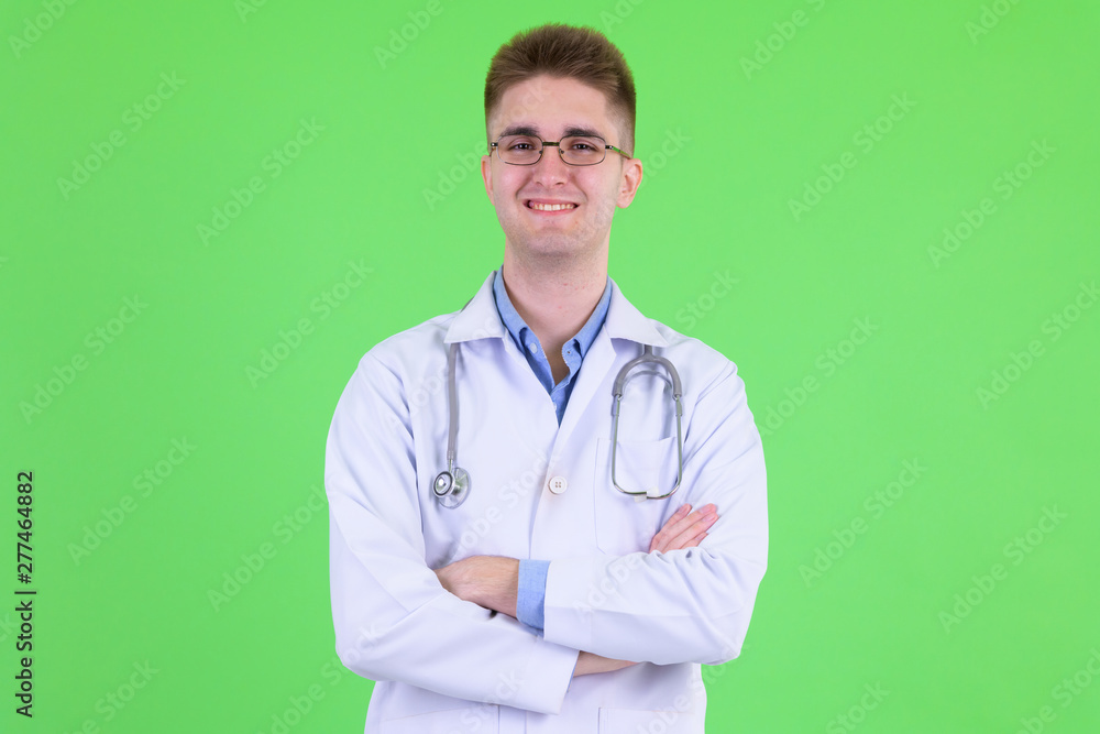 Happy young handsome man doctor smiling with arms crossed Happy young handsome man doctor smiling with arms crossed